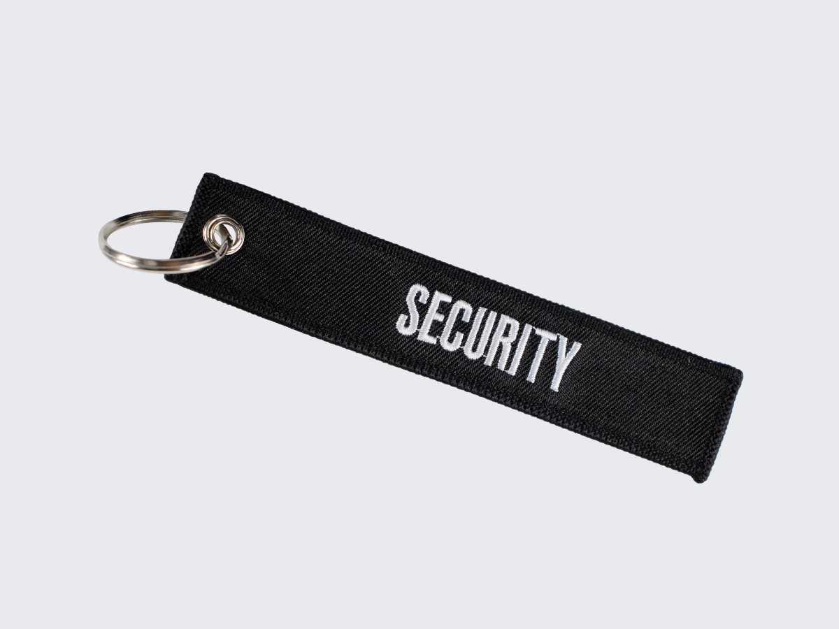 Musta kankainen avaimenperä SECURITY tekstillä. Black fabric keychain with text Security.