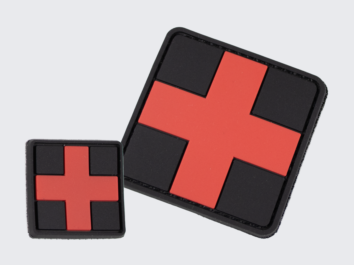 Musta PVC hihamerkki punaisella ristillä. Kaksi eri kokoa. Black PVC patch with a red cross. Two different sizes.
