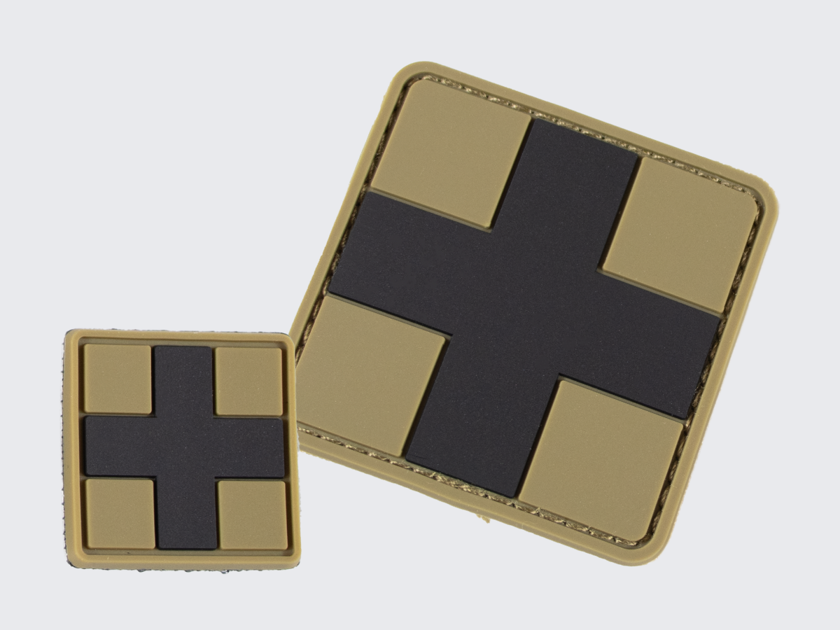 Tan värinen PVC hihamerkki tummalla ristillä. Kaksi eri kokoa. Tan corored PVC patch with a dark cross. Two different sizes.