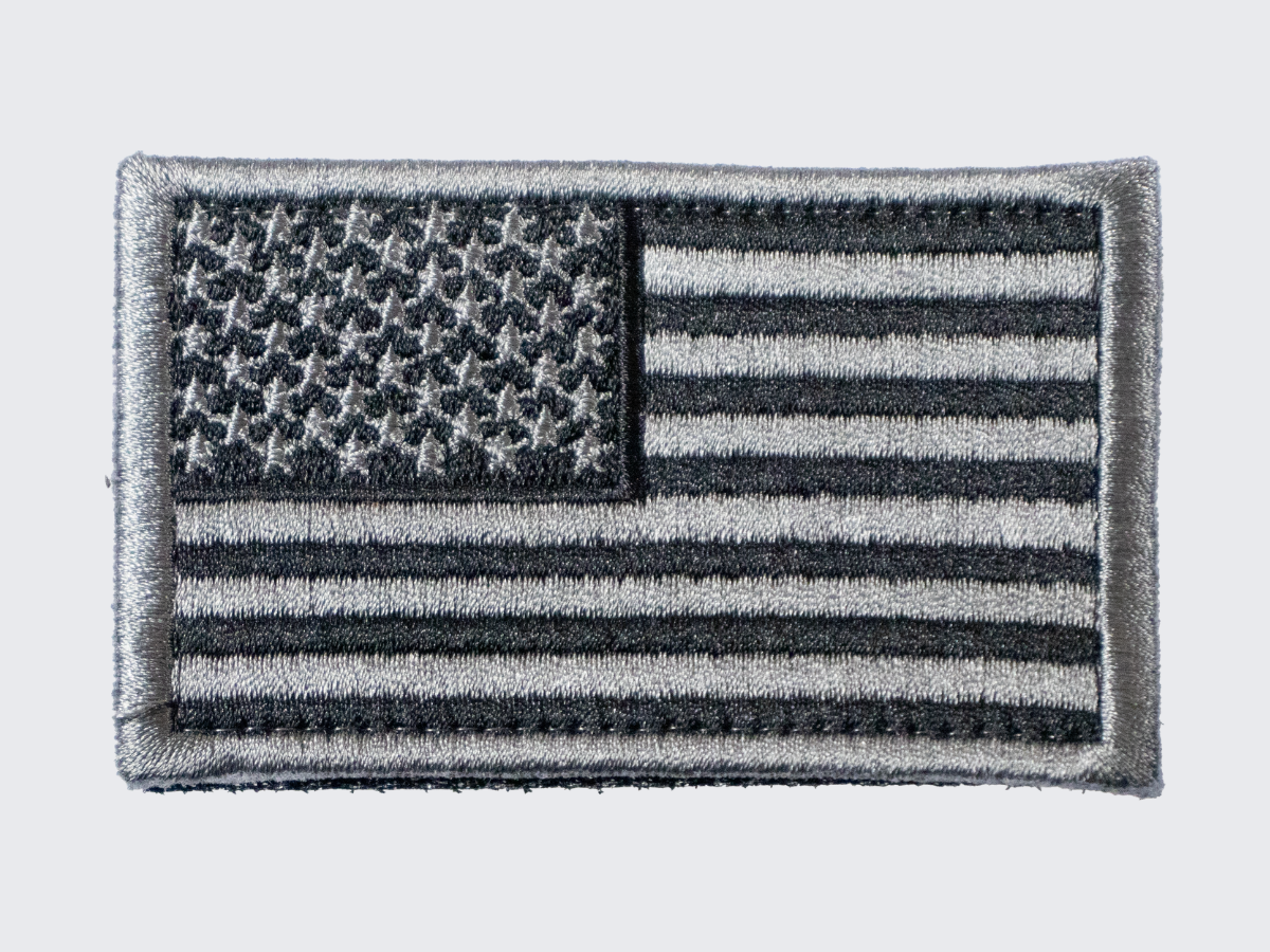 Musta-hopea USA lippu hihamerkki. Svart och silver USA flagga ärm patch. Black and silver USA flag sleeve patch.