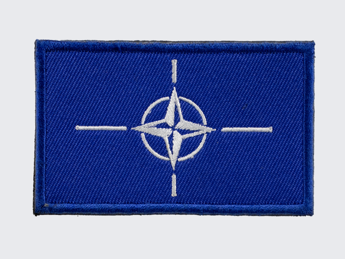 Brodeerattu sinivalkoinen NATO hihamerkki. Embroidered blue and white NATO moral patch. Broderad blå och vit NATO korsärmmärke.