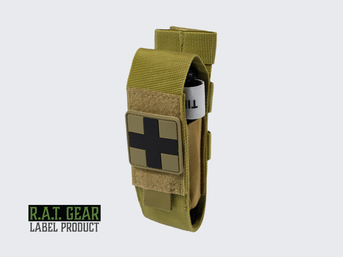 Kiristysside setti ruskealla varustetaskulla, Tourniquet kiristyssiteellä ja ensiapu merkillä. Tourniquet kit with a tan colored tactical pouch, tourniquet, and first aid patch. Tourniquet set med brun utrustningsficka, tourniquet och första hjälpen-märke.