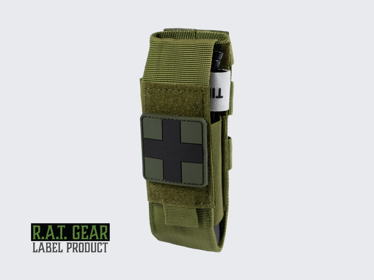 Kiristysside setti vihreällä varustetaskulla, Tourniquet kiristyssiteellä ja ensiapu merkillä. Tourniquet kit with a green tactical pouch, tourniquet, and first aid patch. Tourniquet set med grön utrustningsficka, tourniquet och första hjälpen-märke.