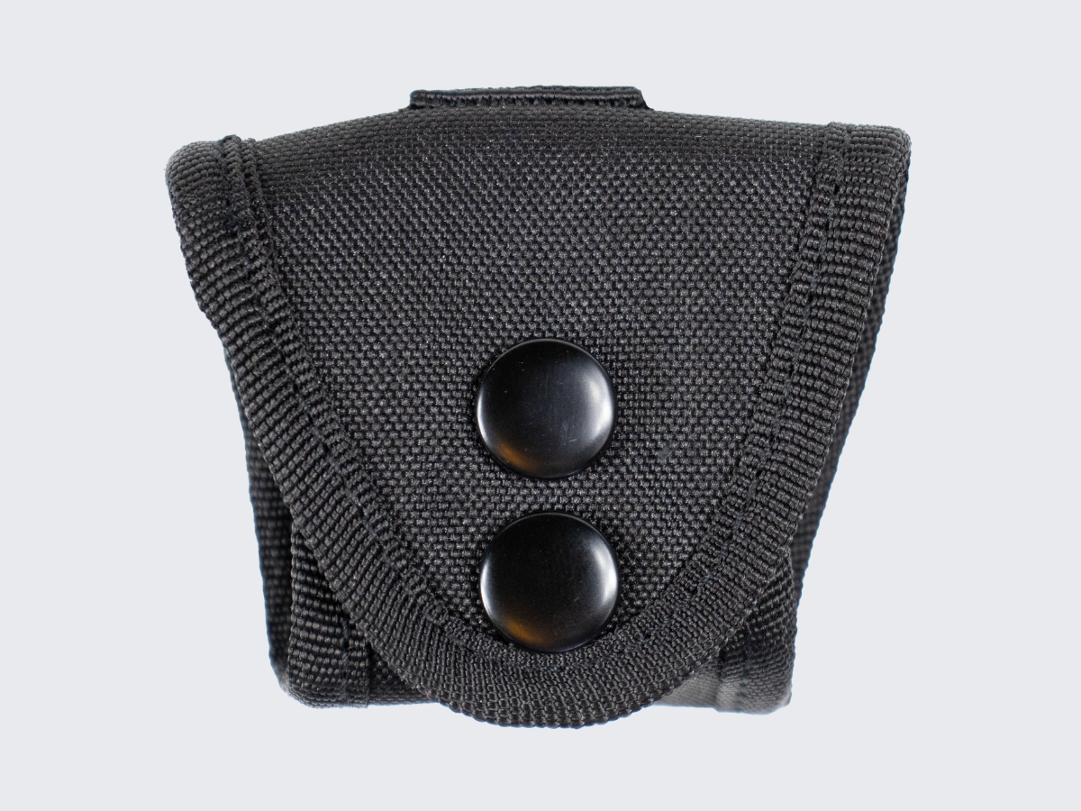 Pienikokoinen ja erittäin kevyt käsirautapidike vartijan tai järjestyksenvalvojan varustevyölle. A compact and extremely lightweight handcuff holder for a guard or security personnel equipment belt.